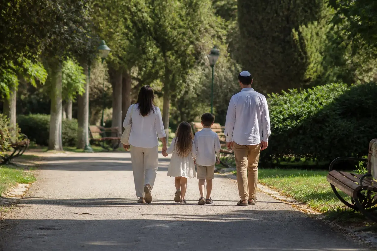 סוף שבוע עם עיסוק אחר מקל לוותר על עוד בדיקה משפחה קטנה הולכת בגינה שכונתית בשבת בבוקר, מצולמת מאחור ממרחק